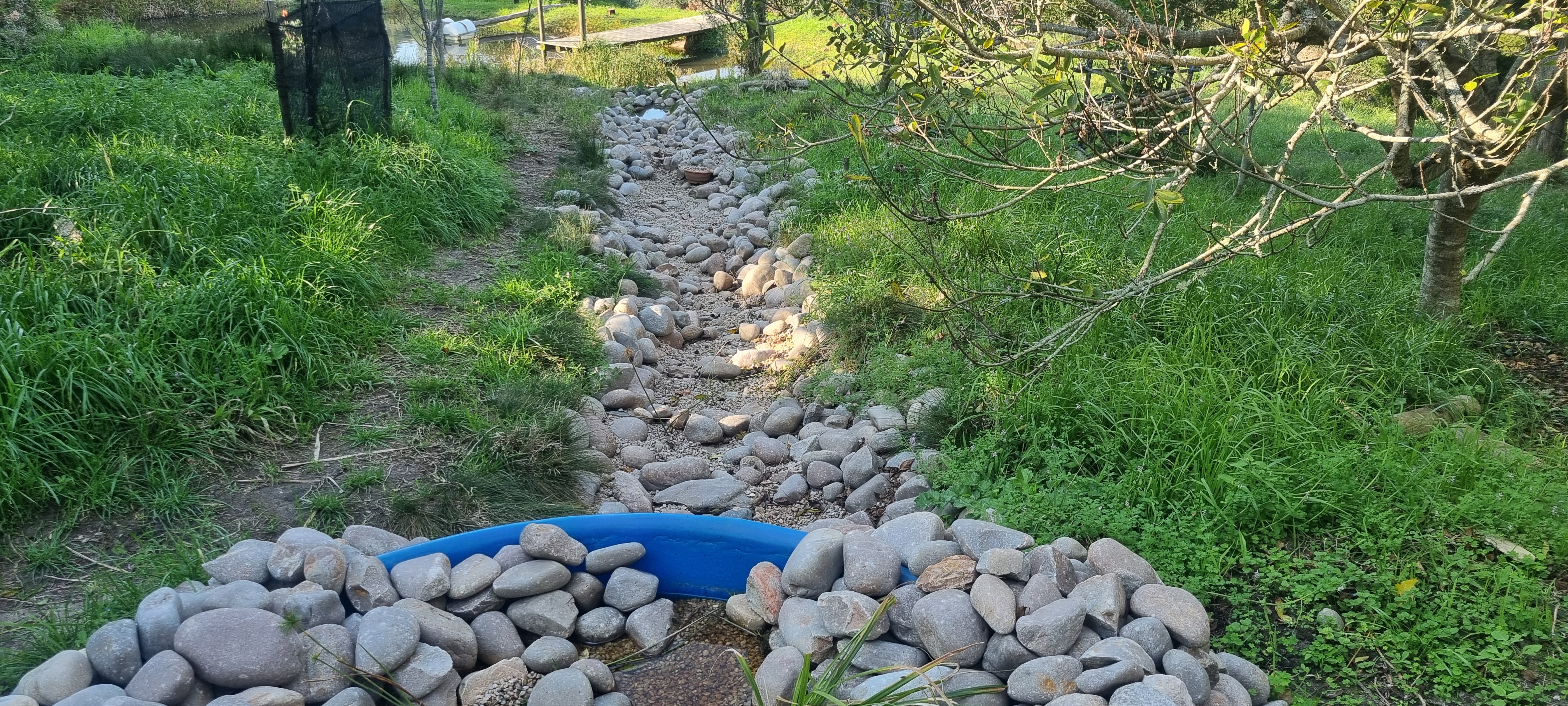 The filtered water travels down a hand-built stone river back into the dam, closing the loop.